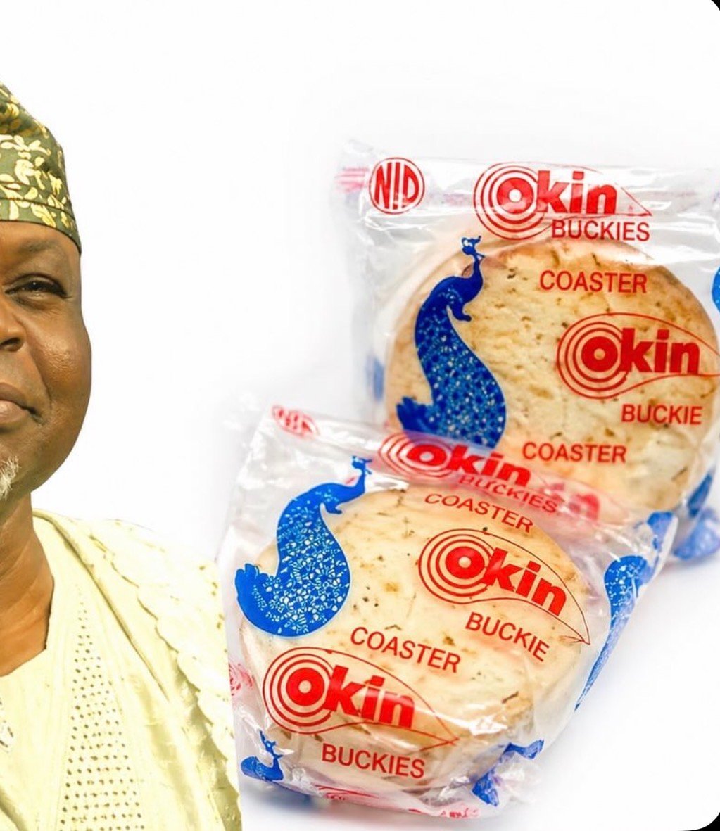 Okin Buckies coaster biscuits package with blue peacock design, held beside a man wearing gold headwear